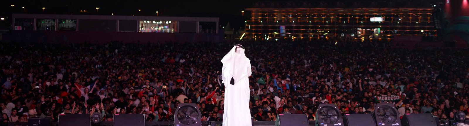 Hamad Al Amari on stage facing the crowd at the FIFA Fan Festival